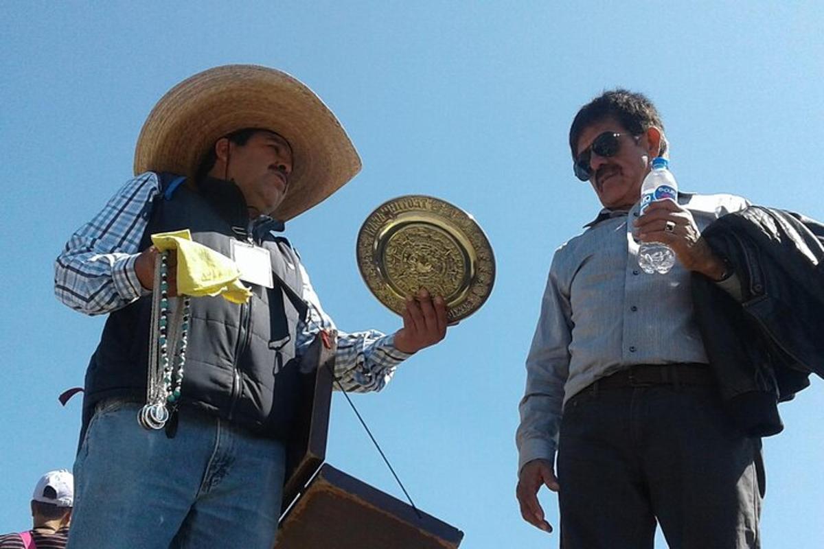two men standing next to each other holding a trophy