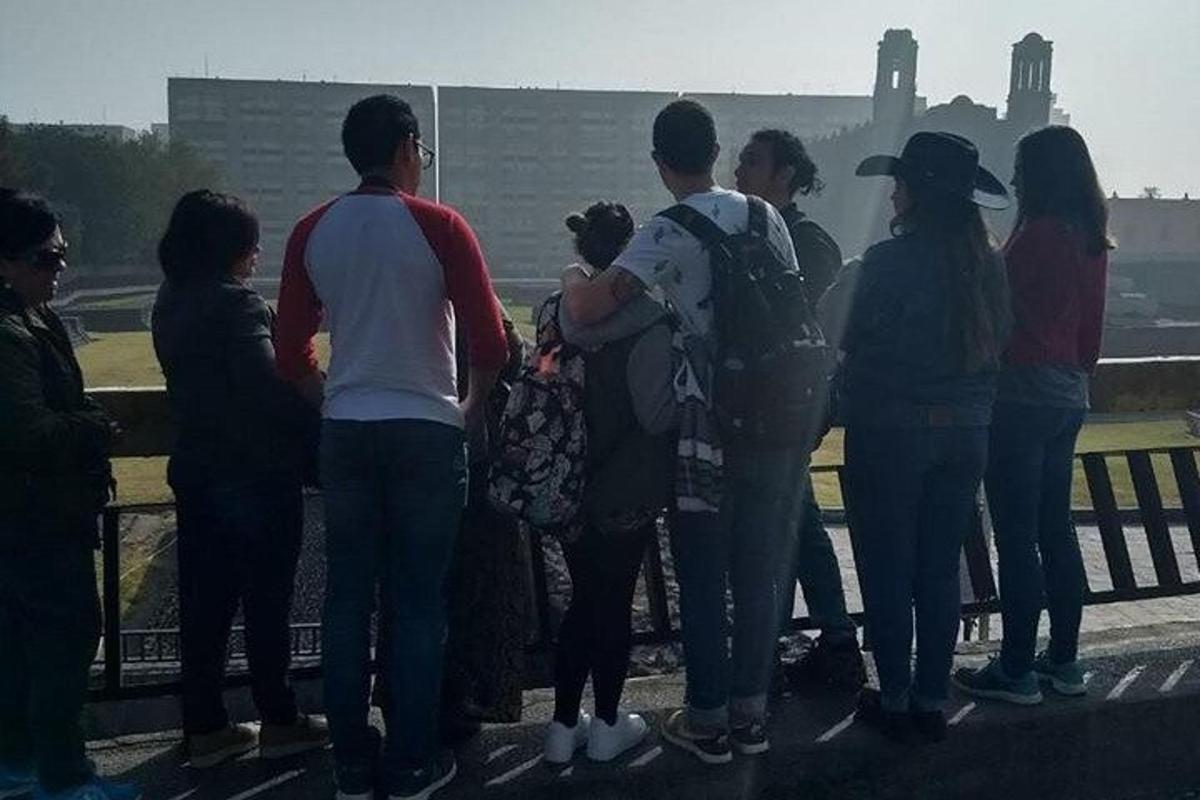 a group of people standing on a fence looking at the water