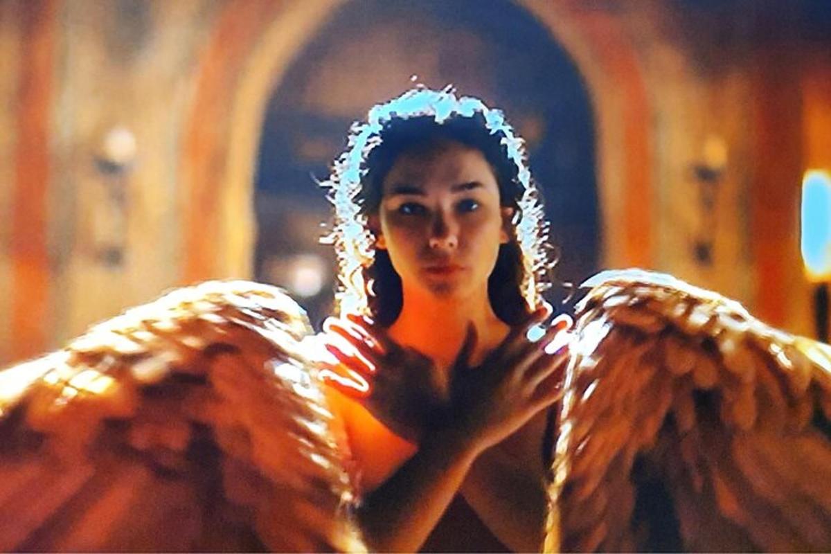 Una mujer con alas de ángel frente a un espejo.