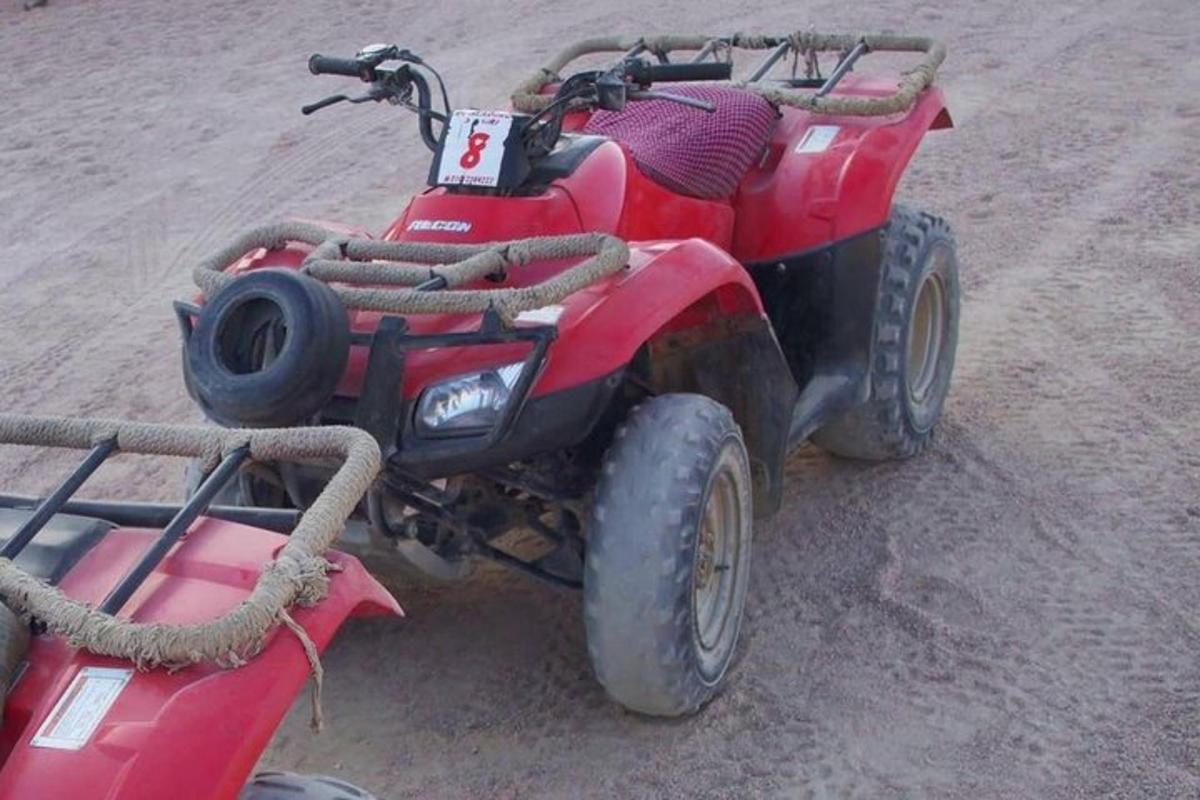 a red four wheeler parked in the sand