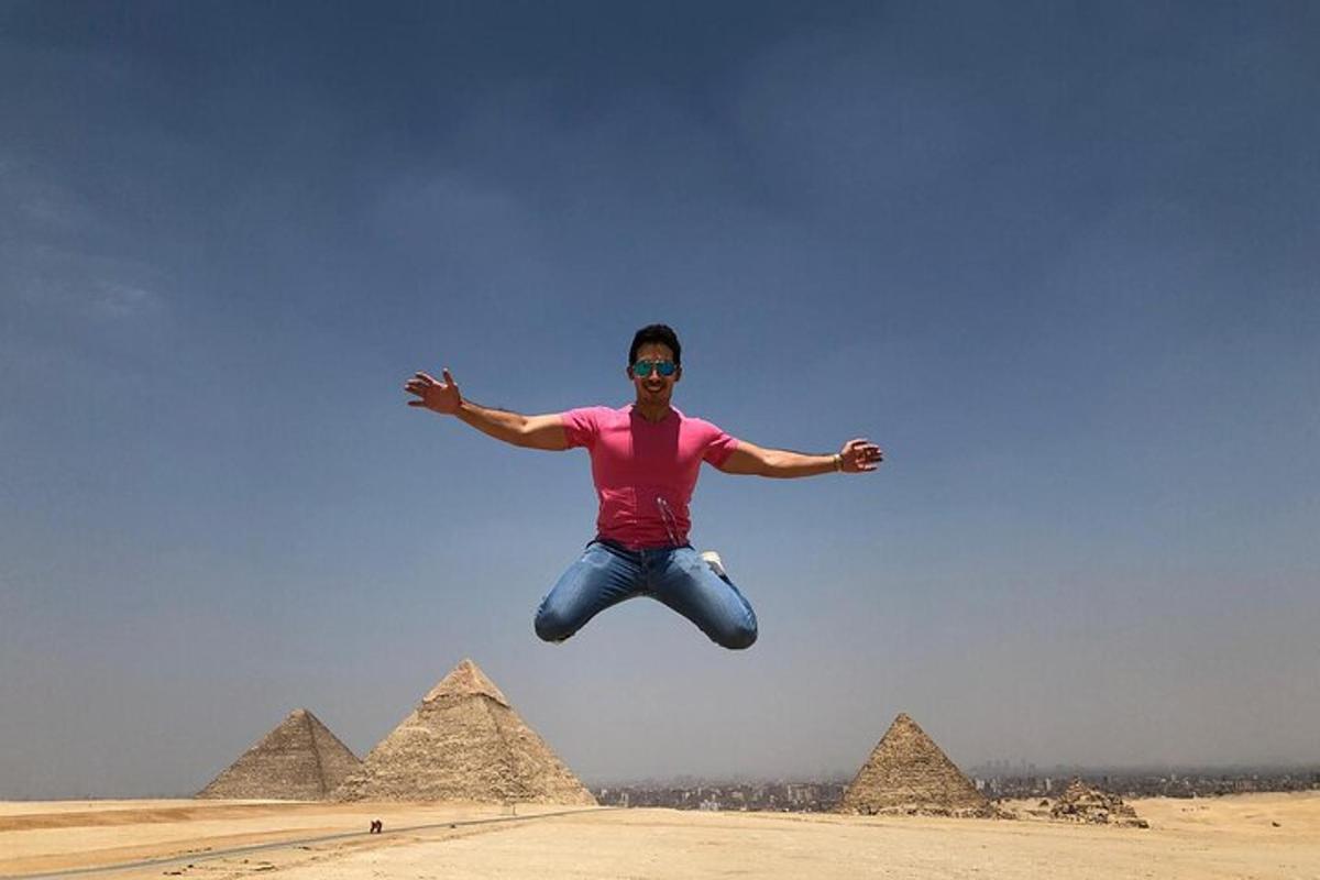muž skákající do vzduchu před pyramidami