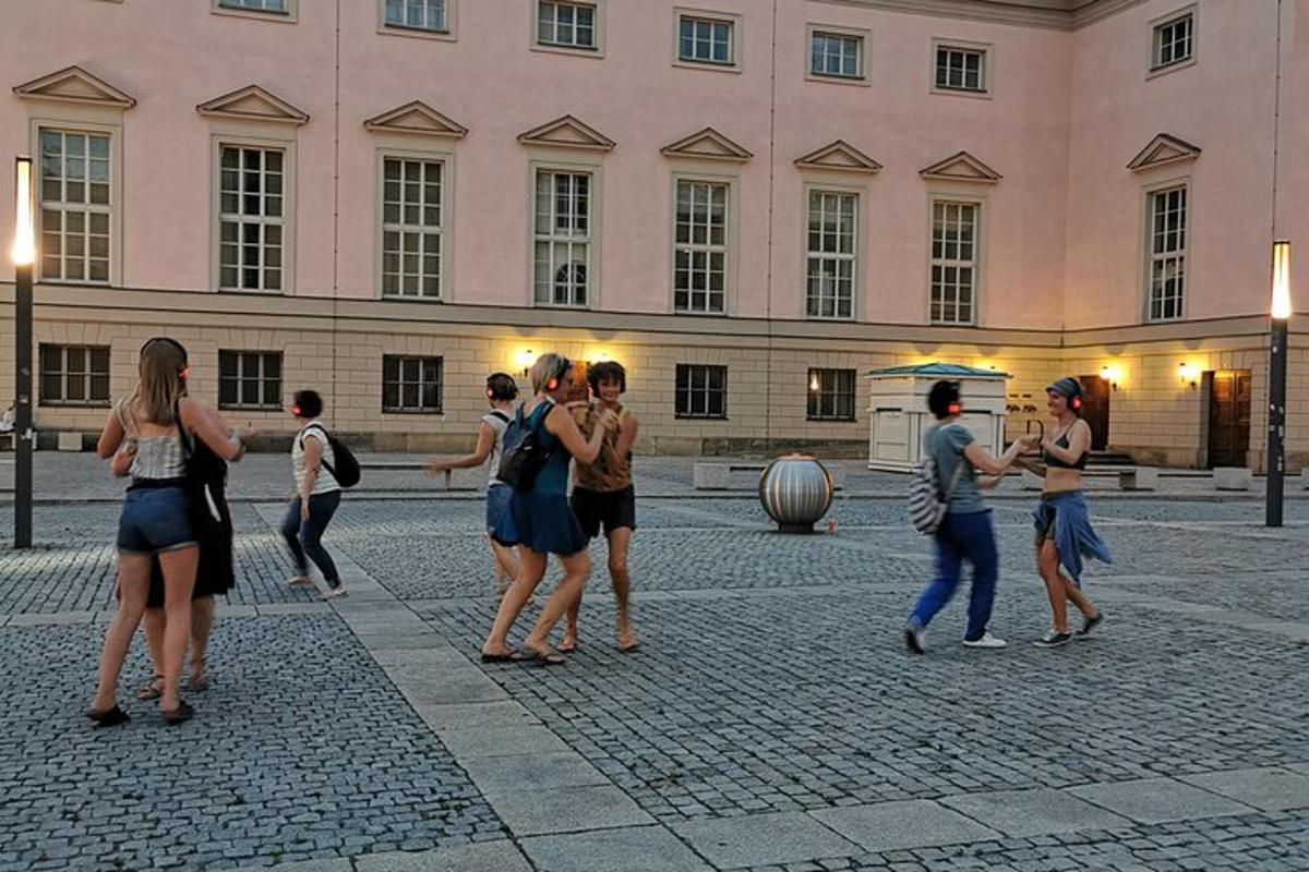 un grup de oameni care dansează în fața unei clădiri