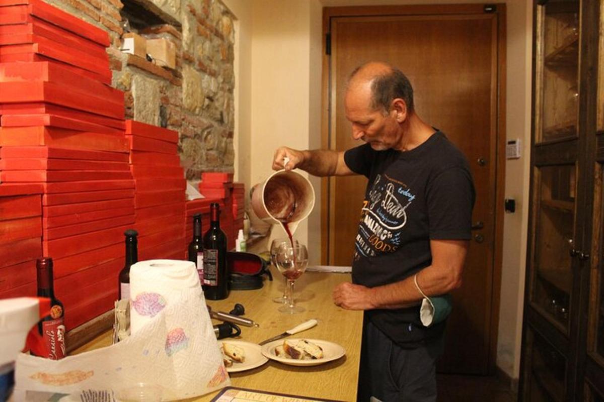 un uomo in piedi in cucina che prepara un bicchiere di vino