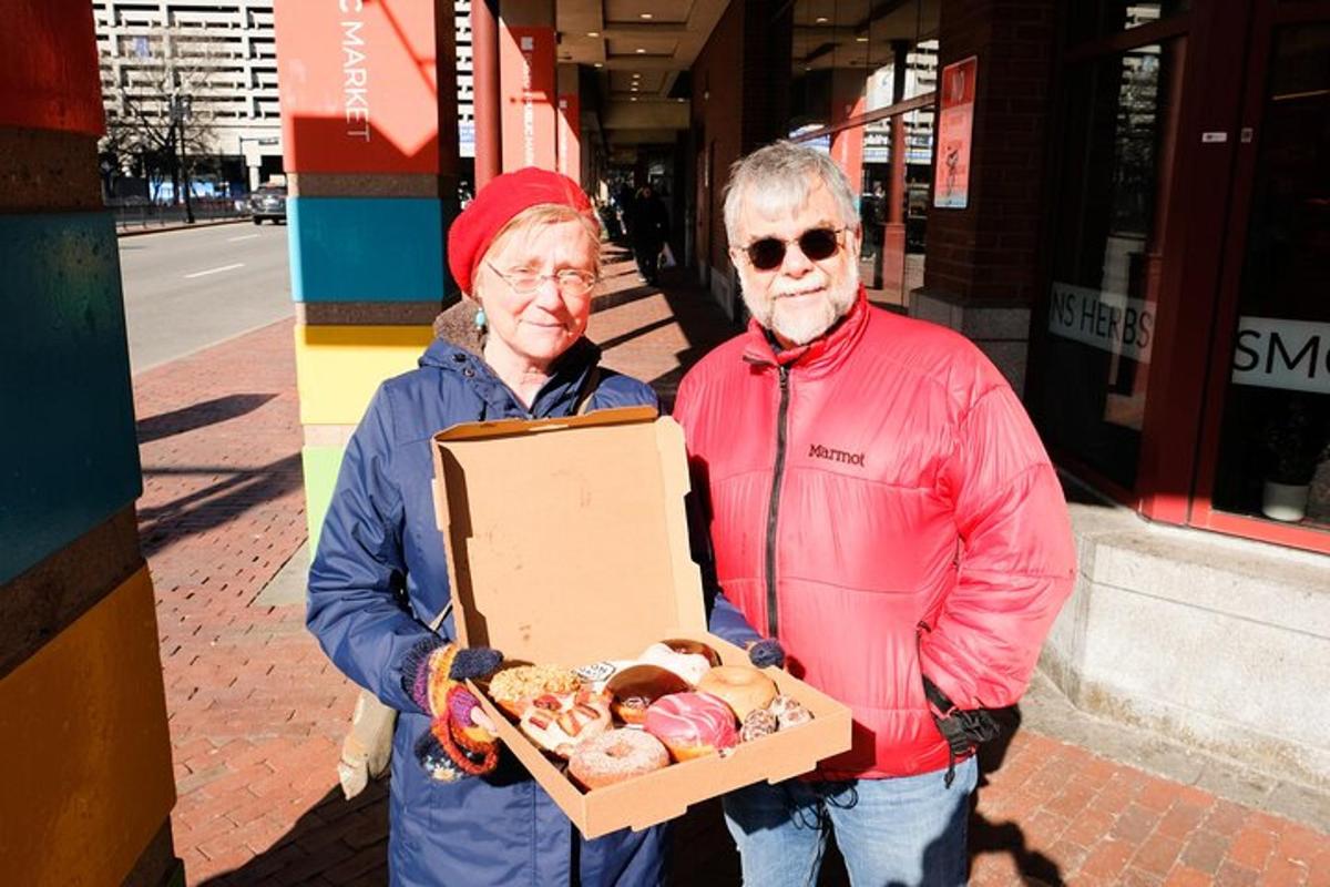 um homem e uma mulher mais velhos segurando uma caixa de donuts