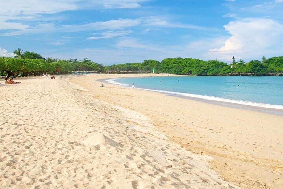 o plajă cu oameni care stau pe nisip și ocean
