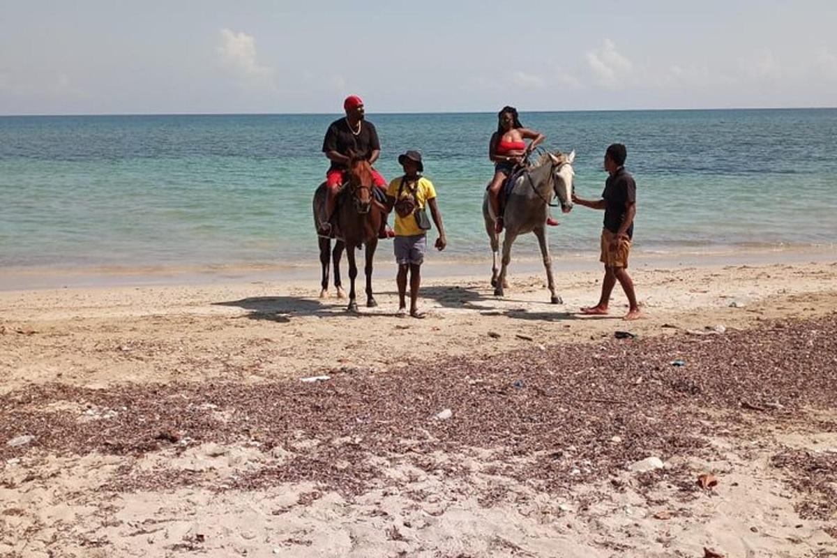 a group of people riding horses on the beach