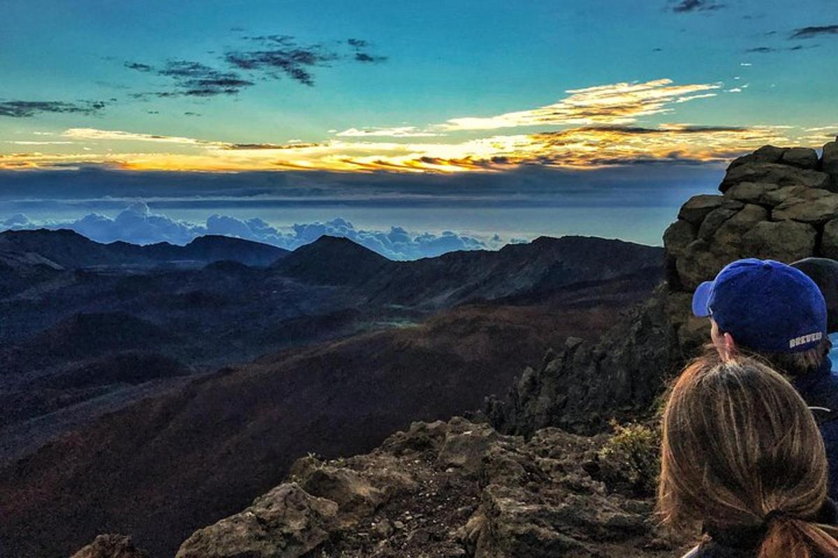 a woman sitting on top of a mountain looking at the view