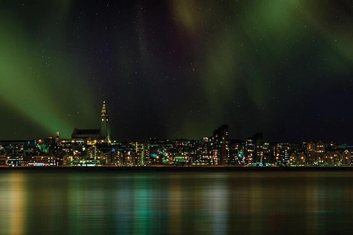 uma cidade à noite com luzes verdes no céu