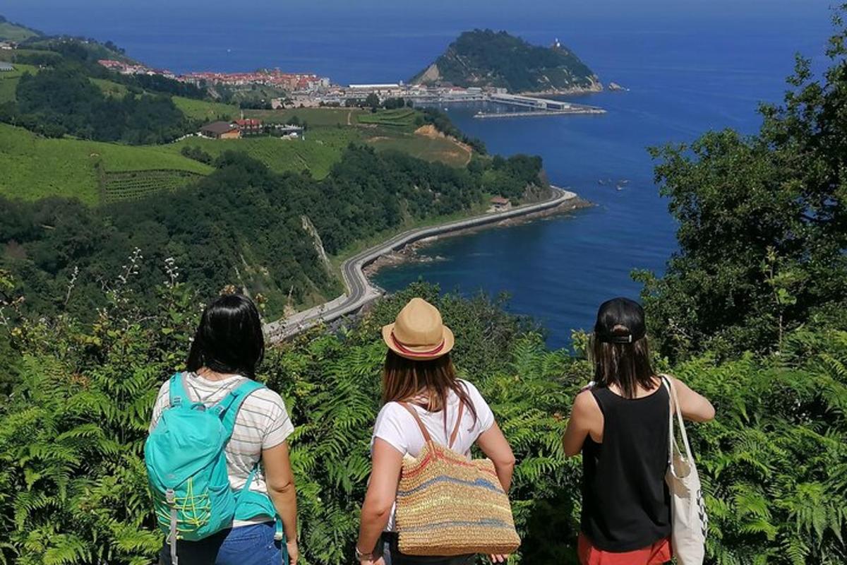 tre donne in piedi su una collina che guardano l'oceano