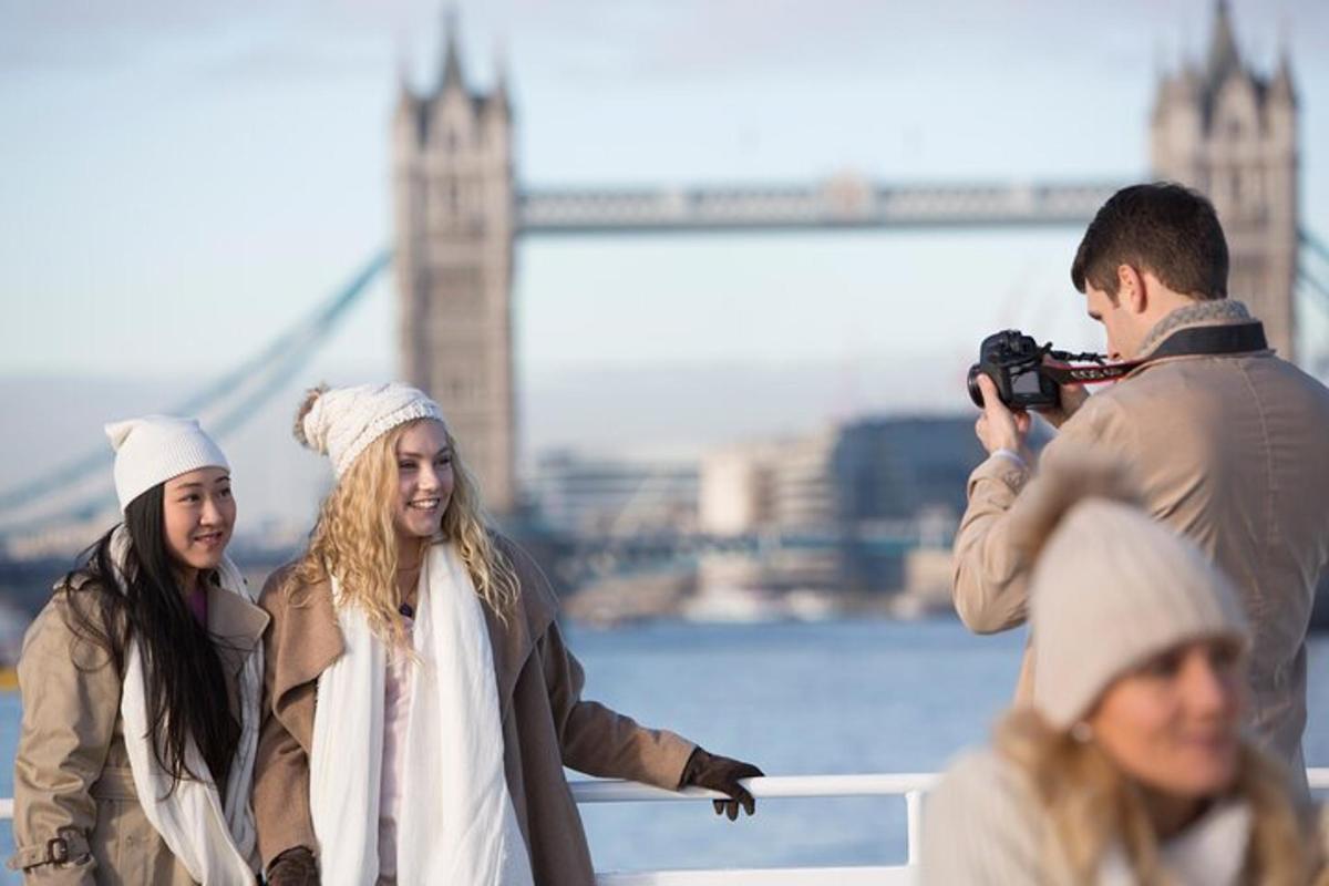 en man som tar en bild av två kvinnor framför Tower Bridge