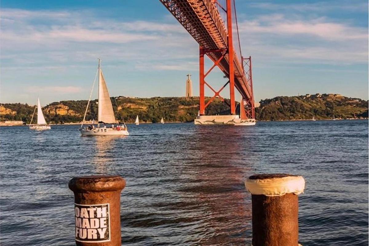 dois barcos na água perto de uma ponte com veleiros