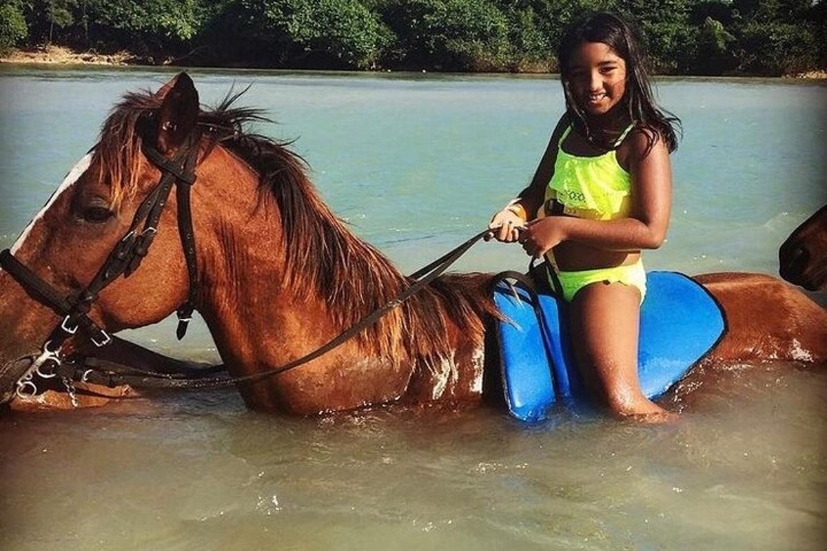 فتاة صغيرة تجلس على حصان في الماء