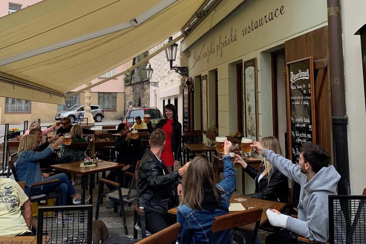cilvēku grupa, kas sēž pie galdiņiem restorānā