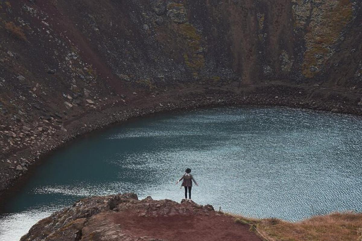 seseorang berdiri di atas batu di depan danau