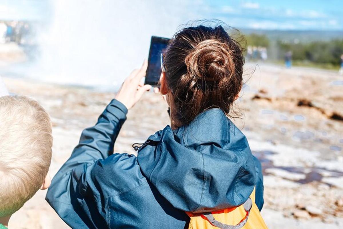 una donna che scatta una foto con il suo cellulare in spiaggia