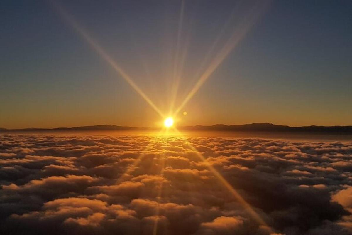 a view of the sun rising above the clouds