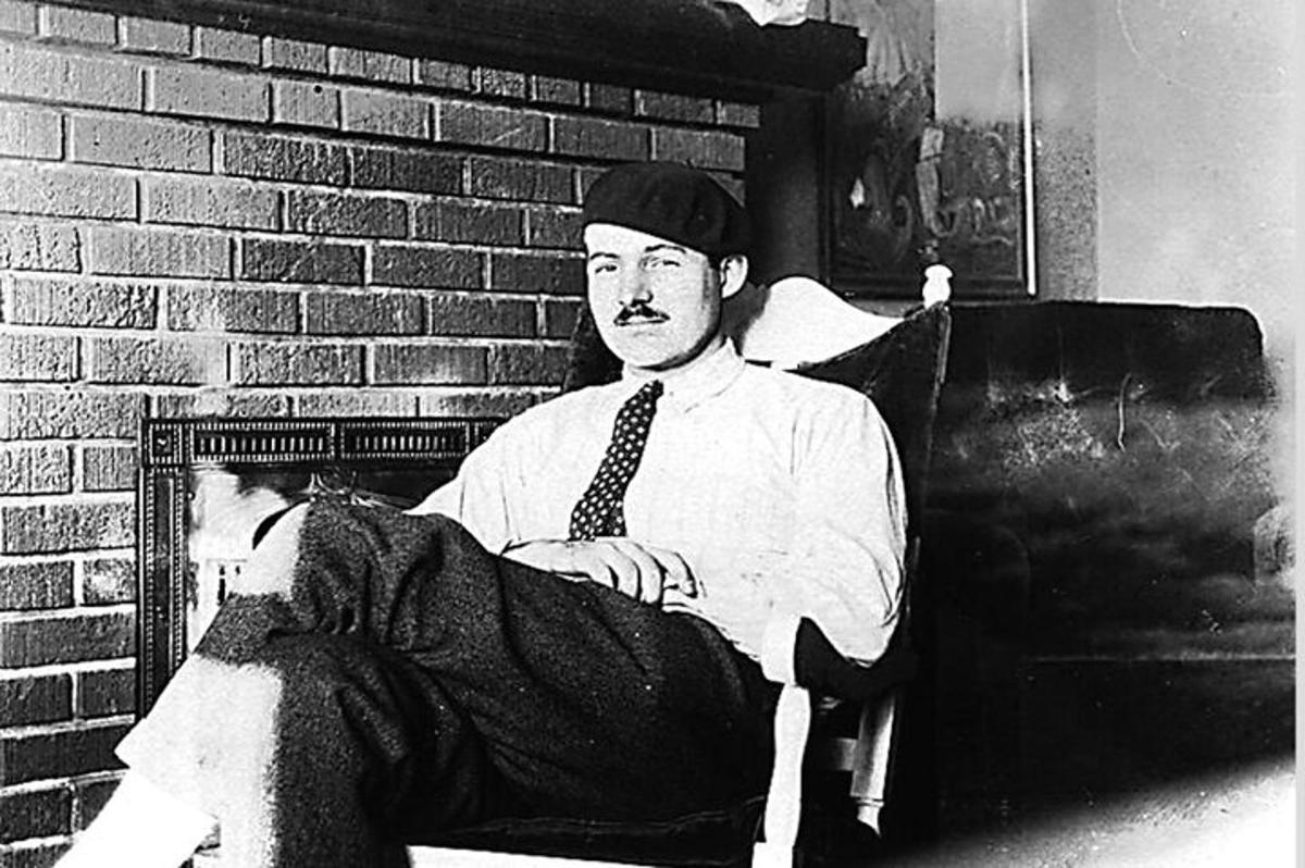 a man sitting in a chair wearing a hat and tie