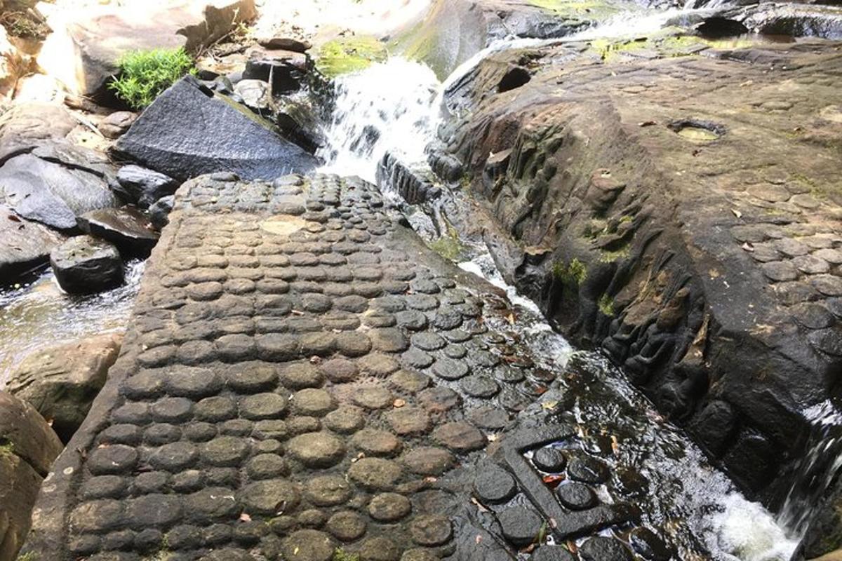 aliran air dengan jalan berbatu di samping air terjun