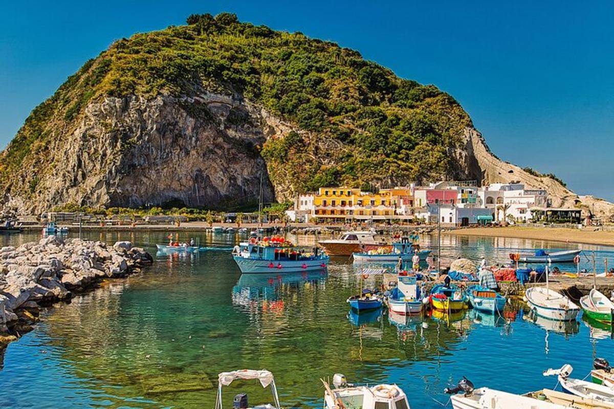 Un grupo de barcos atracados en un puerto junto a una montaña.
