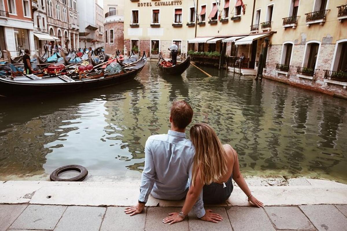 un uomo e una donna seduti accanto a un canale con le gondole