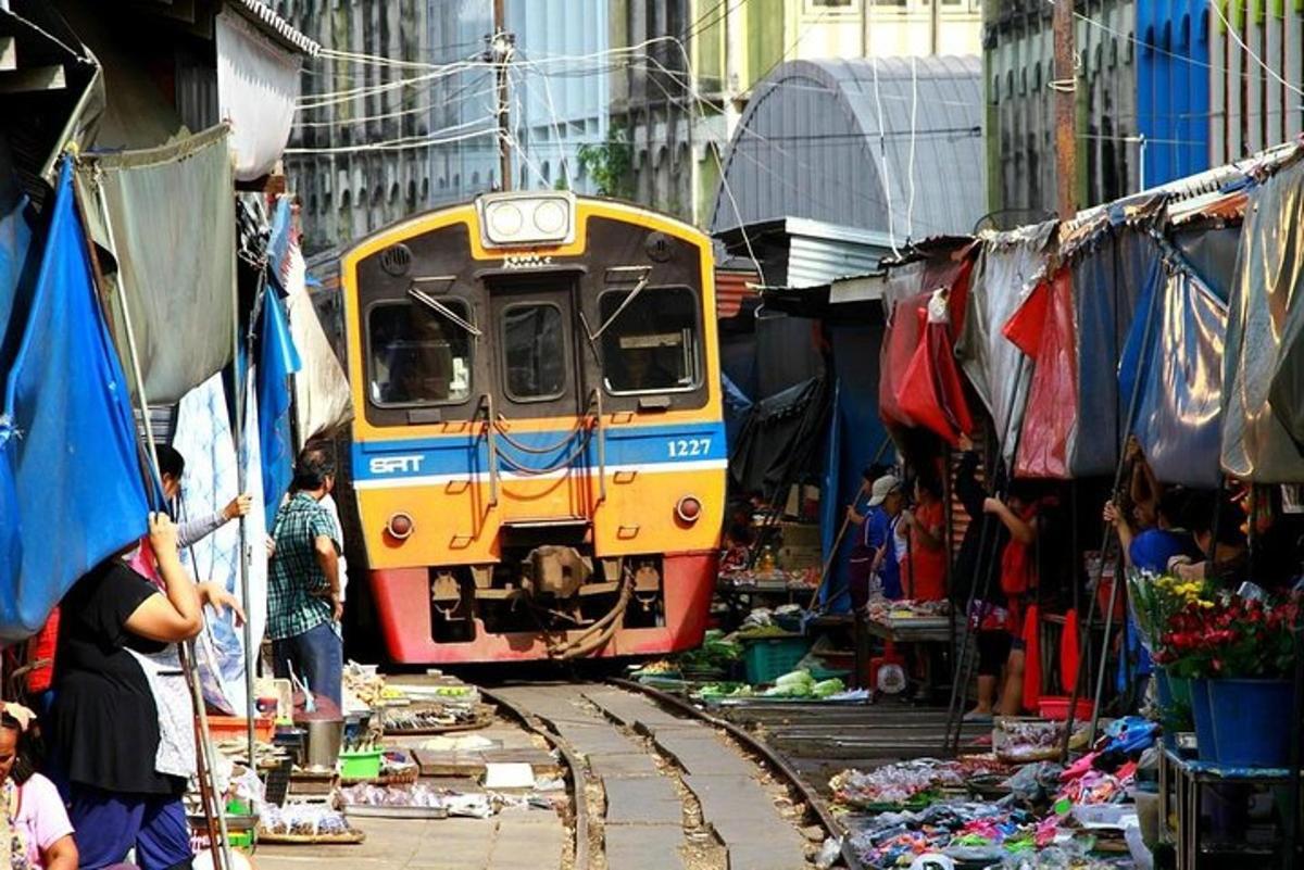 un treno che attraversa un mercato con persone in piedi intorno