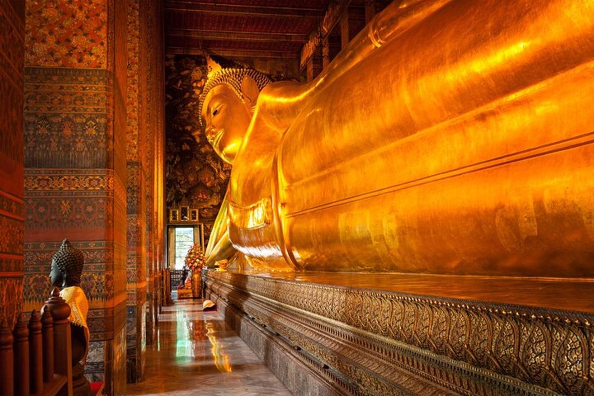 một người ngồi trước một bức tượng lớn trong một tòa nhà