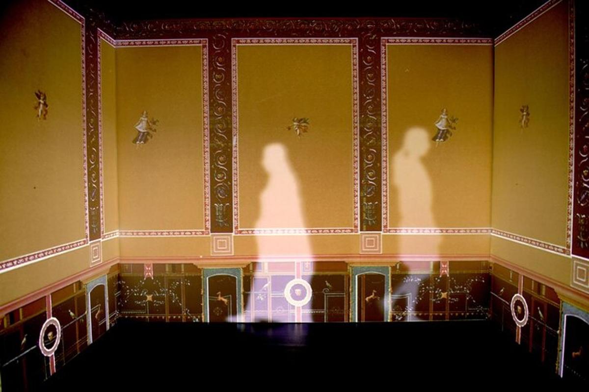an empty room with a stage with the shadows of people