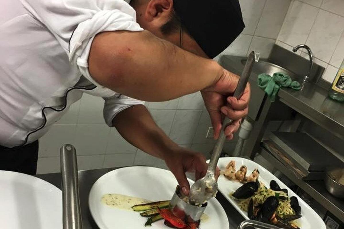 un uomo che prepara il cibo su un piatto in cucina