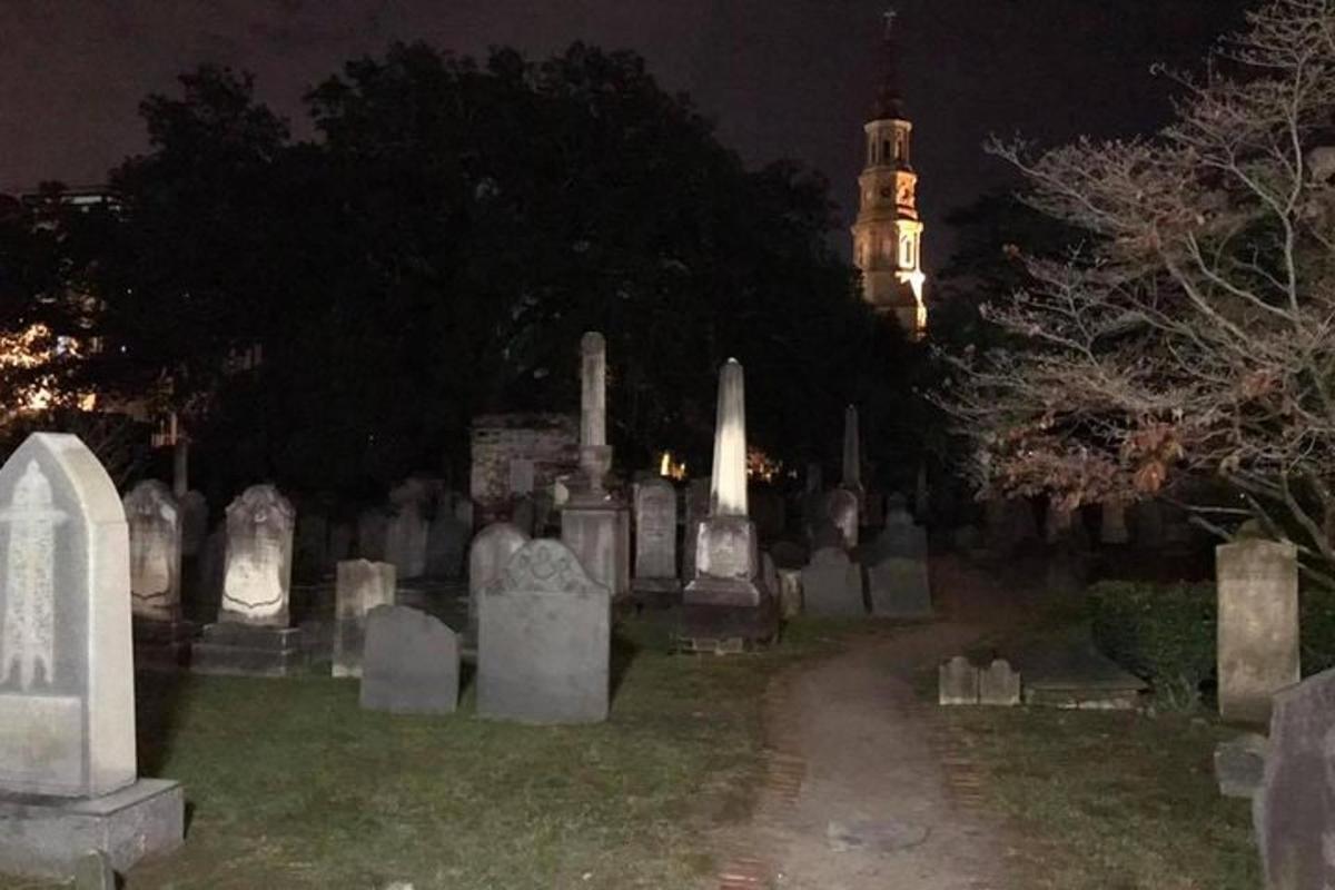 a cemetery at night with a clock tower in the background