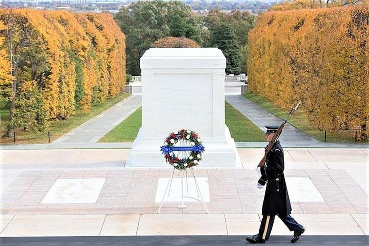 um homem uniformizado passando por um memorial de guerra