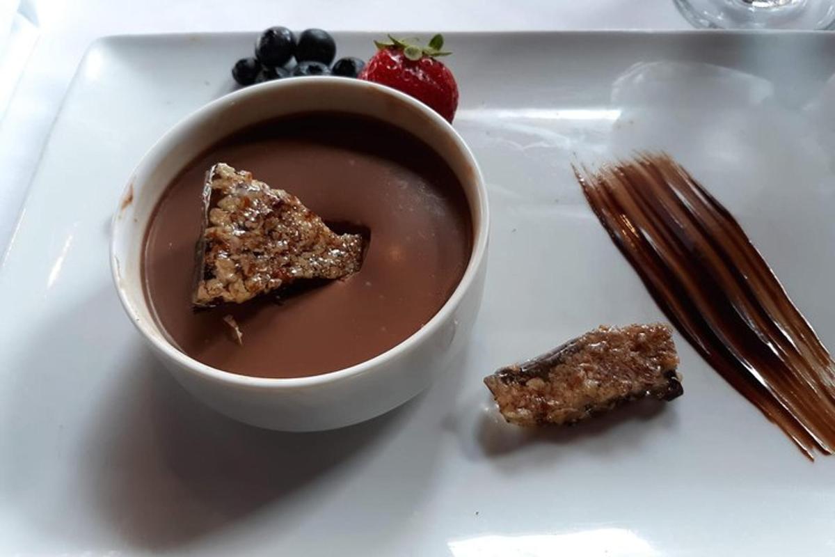 a white plate with a bowl of chocolate pudding and fruit