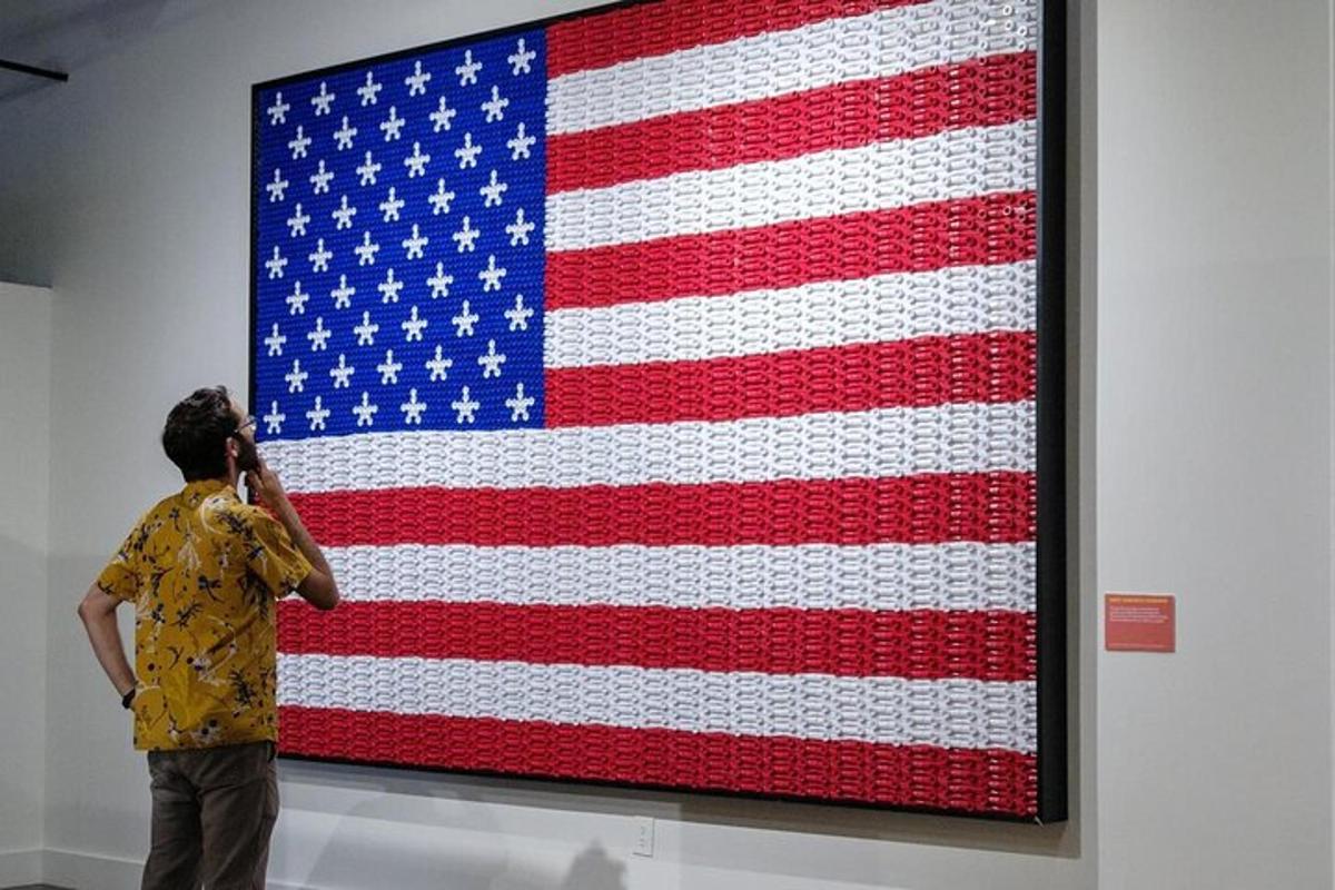 a man talking on a cell phone in front of an american flag painting
