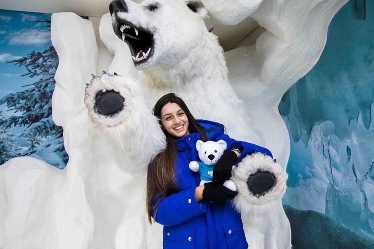 a woman holding a teddy bear in front of a polar bear statue