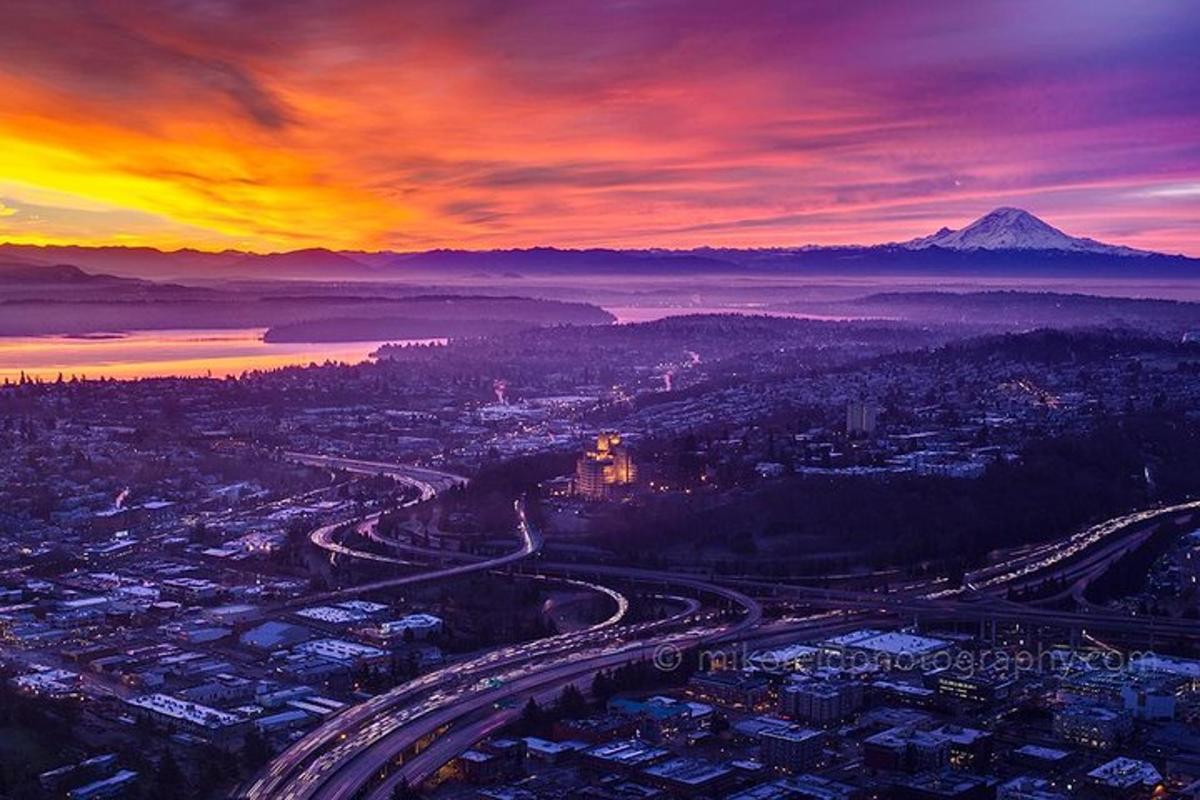 a sunset over a city with a mountain in the background