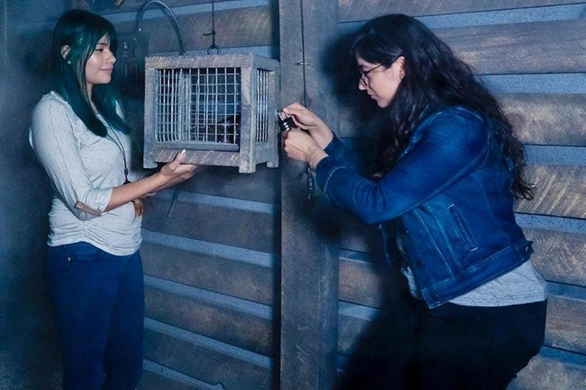two women are standing next to a bird cage