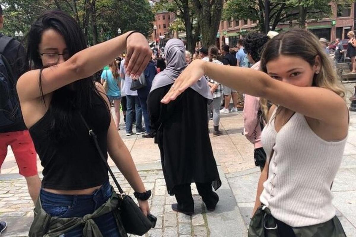 dve mladi ženski, ki stojita na ulici z iztegnjenimi rokami