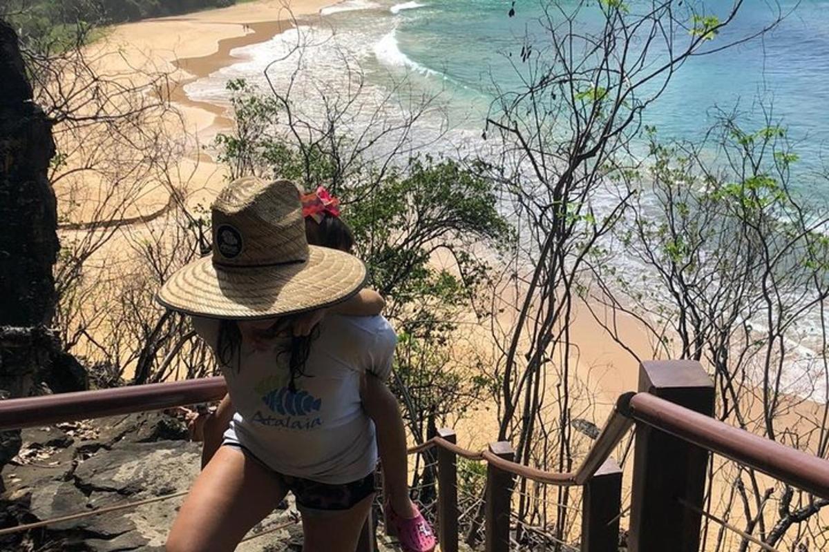 a woman wearing a hat looking down at the beach