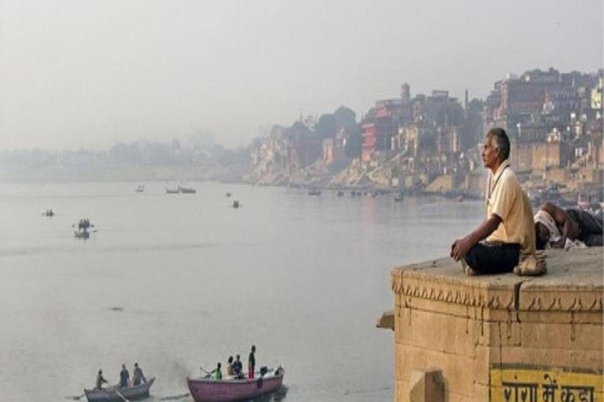 a man sitting on a wall next to a river
