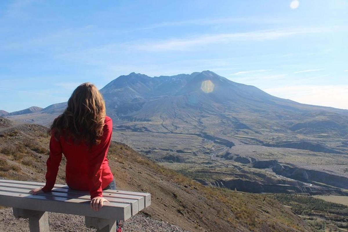 una donna seduta su una panchina che guarda una montagna