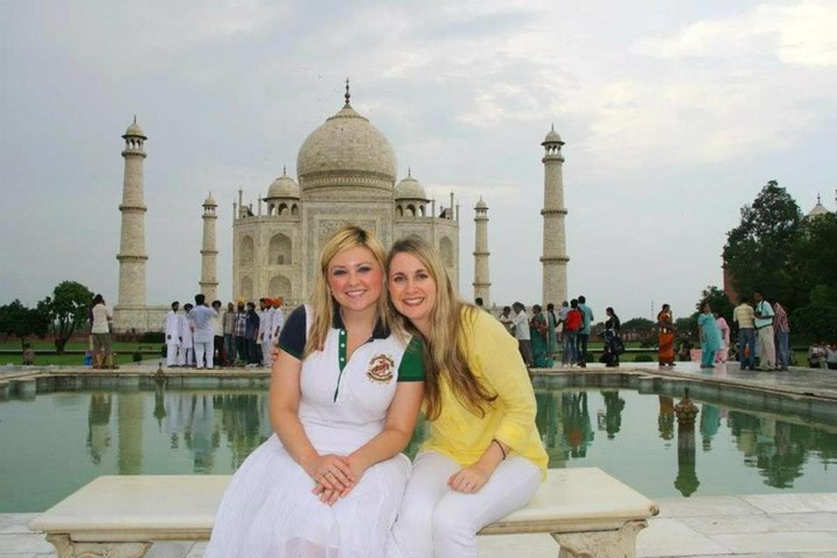 two women sitting on a bench in front of a building