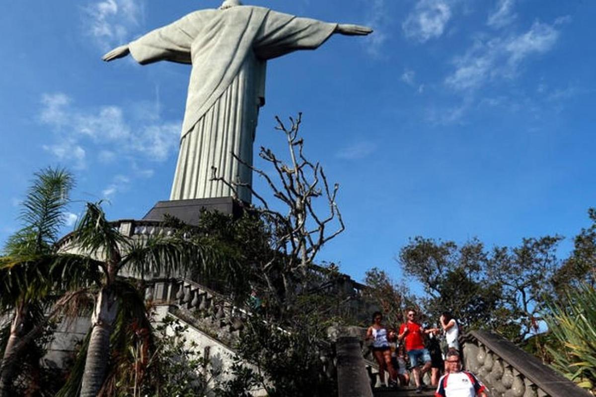 Personas de pie frente a la estatua del Cristo Redentor