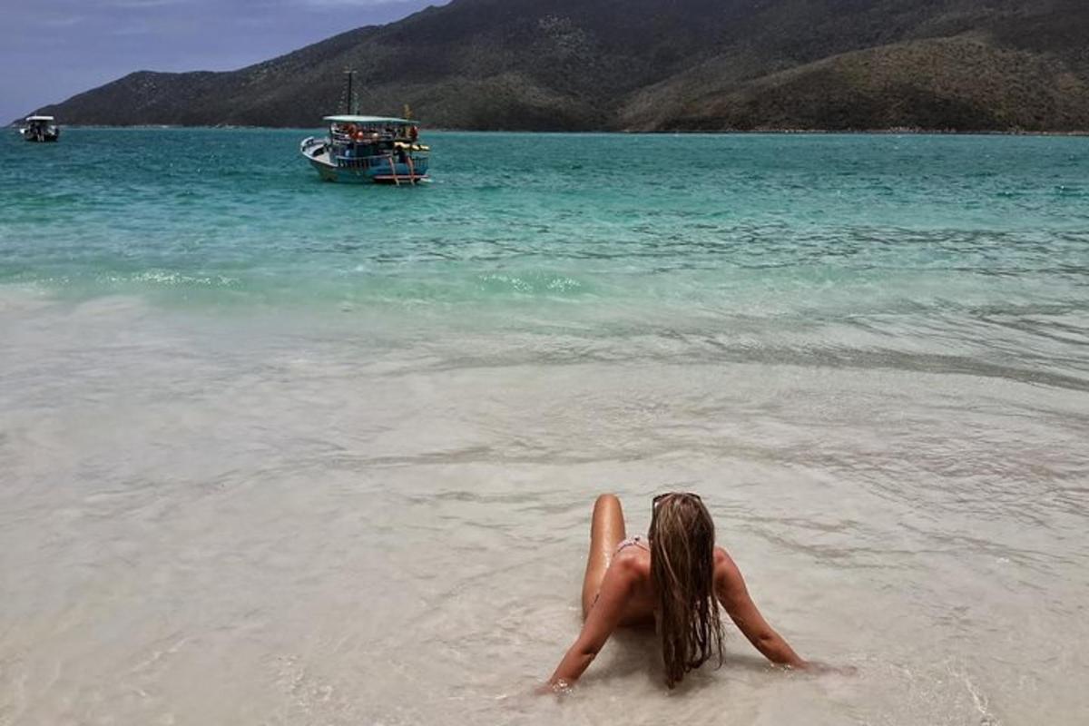 Una mujer tumbada en el agua en una playa con un barco