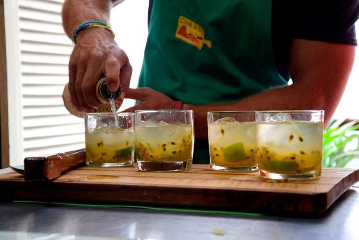 Un hombre preparando tres vasos de bebida en una bandeja de madera.