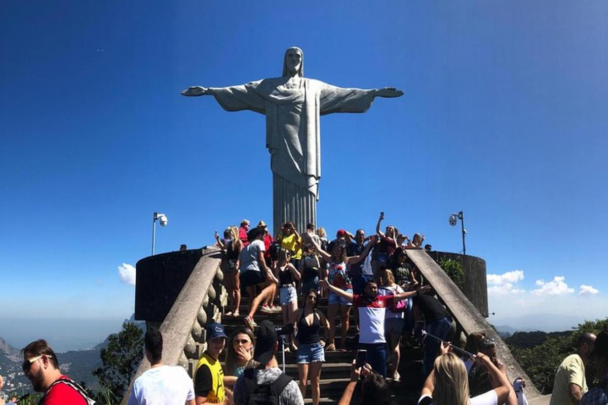 people crowd around the statue of christ the redeemer