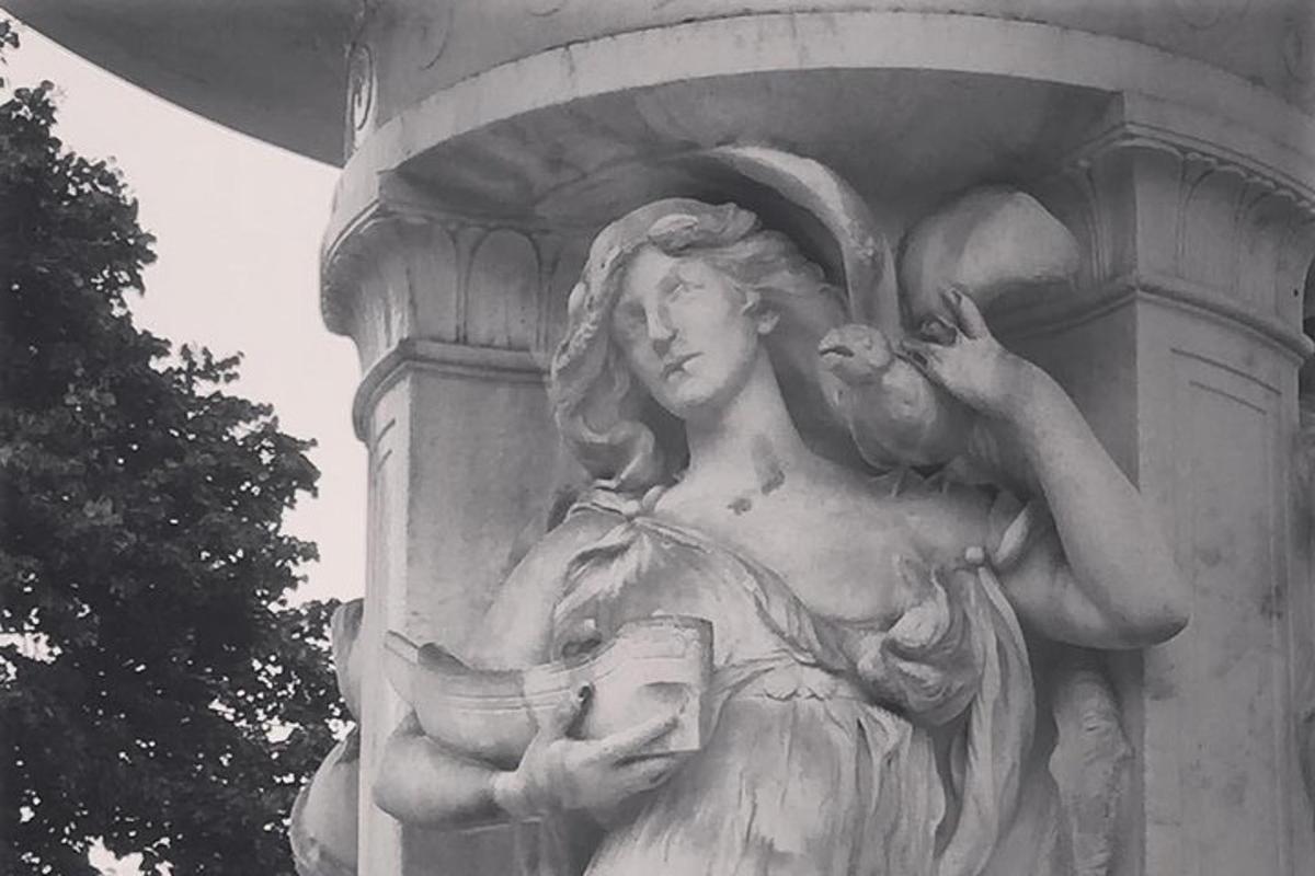 Una estatua de una mujer sosteniendo un pájaro en un monumento.