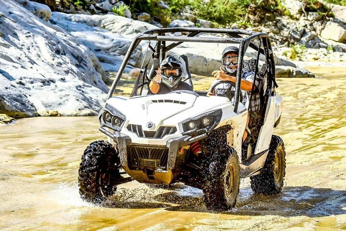 dua orang di dalam ATV yang melaju melewati air
