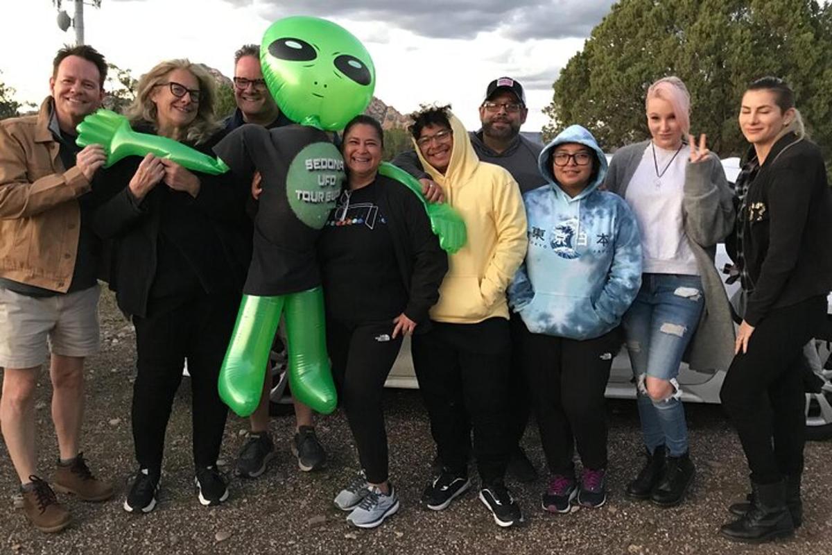 un gruppo di persone in posa per una foto con una mascotte verde