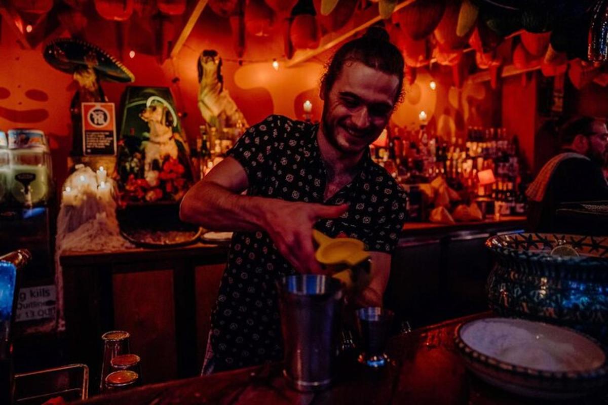 um homem parado em um bar preparando uma bebida