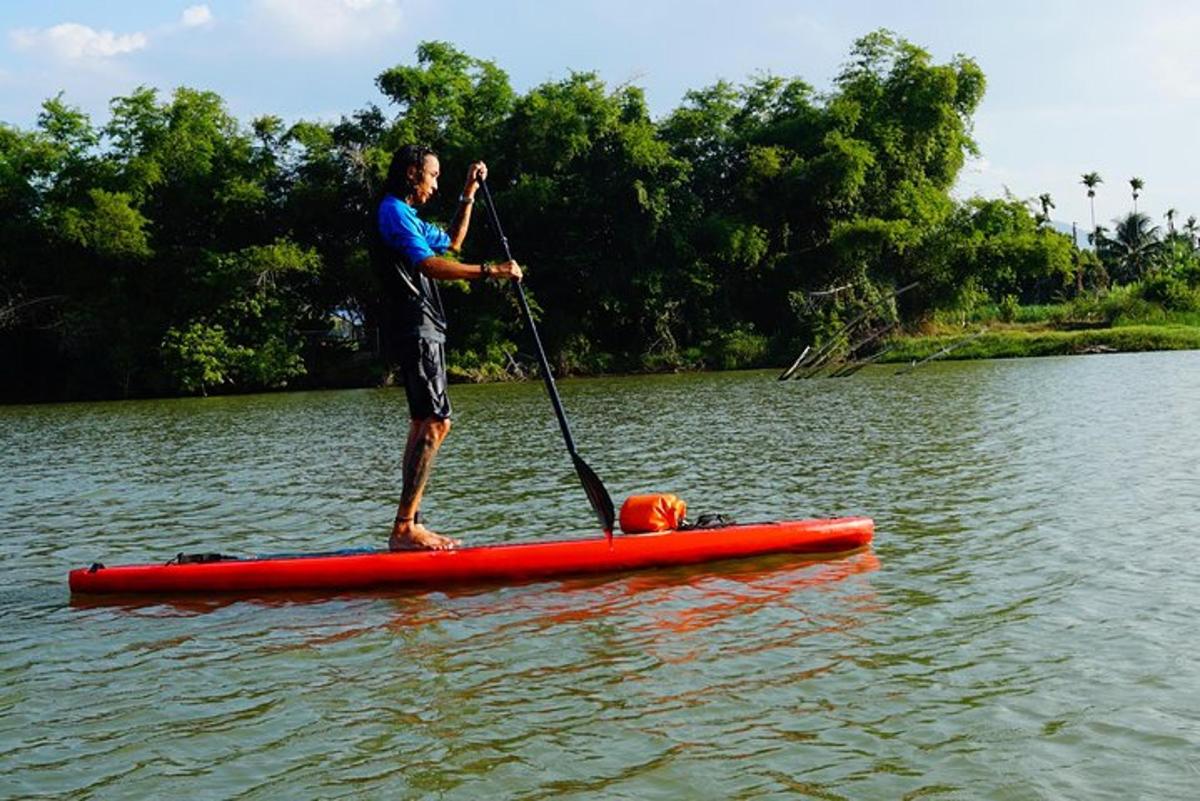muž stojící na paddleboardu ve vodě