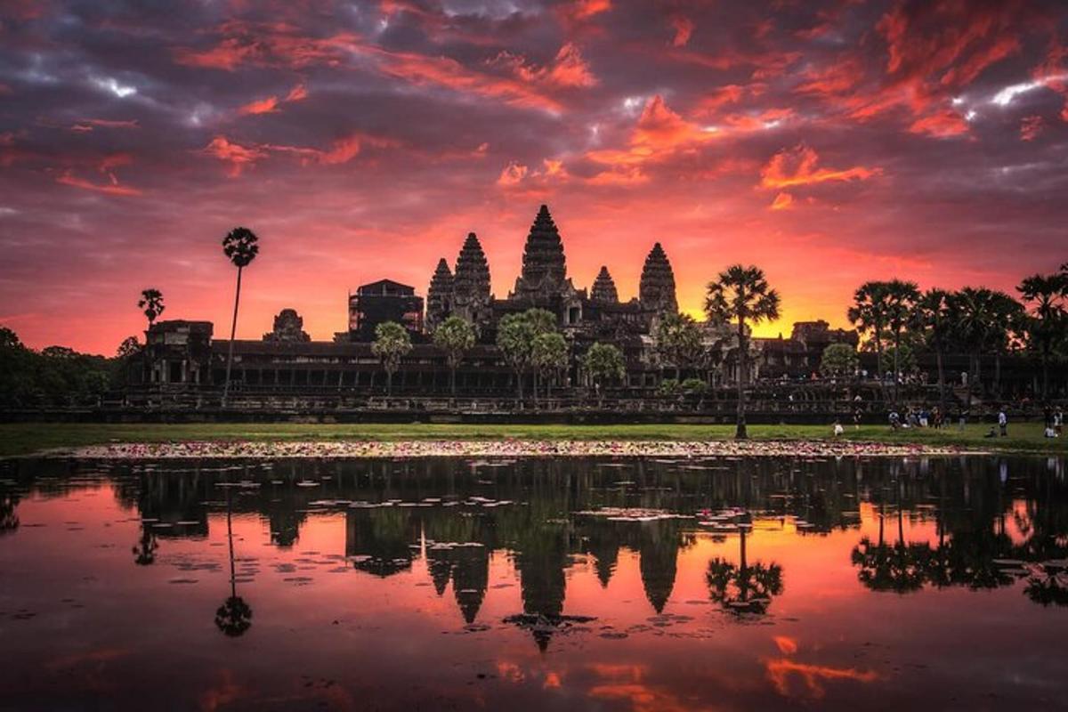 a sunset over a pond in front of a temple